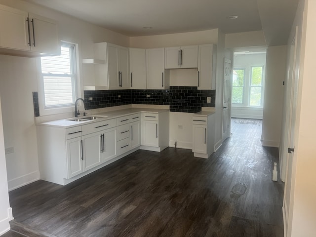 kitchen with dark wood-type flooring, backsplash, sink, and white cabinetry