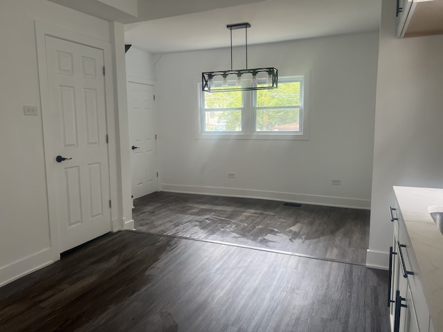 unfurnished dining area with a chandelier and dark hardwood / wood-style floors