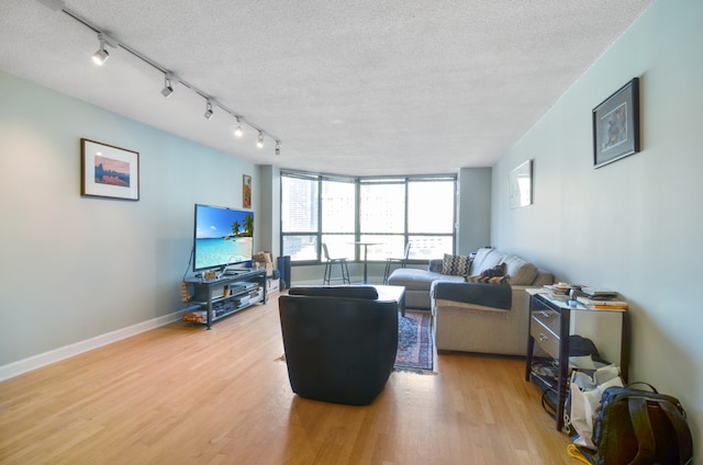 living room featuring a textured ceiling, rail lighting, and light hardwood / wood-style flooring