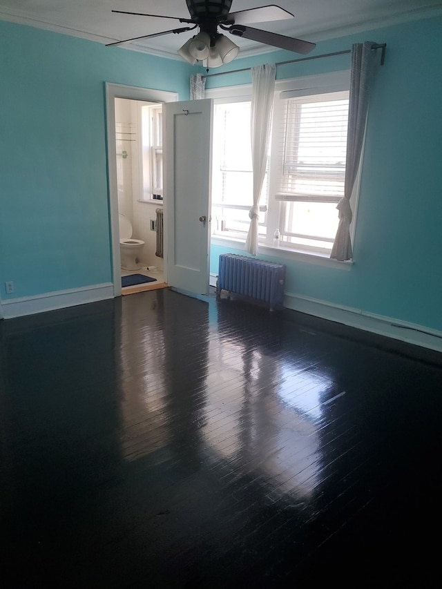 empty room featuring crown molding, wood-type flooring, radiator, and ceiling fan