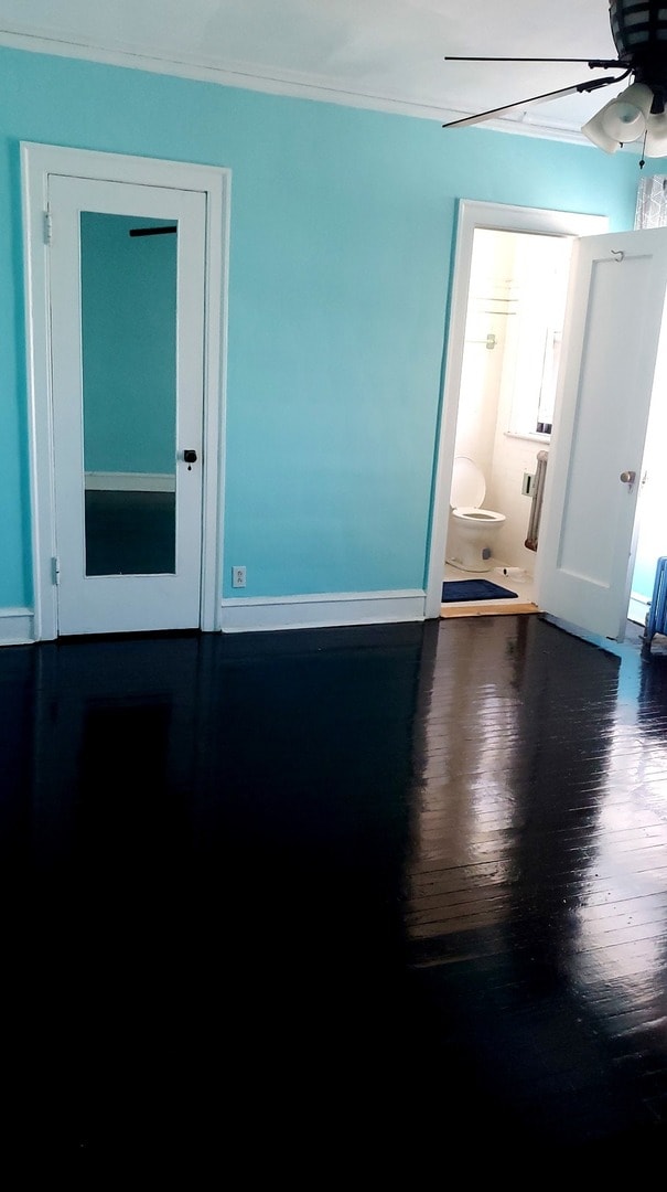 interior space with ornamental molding, ceiling fan, and dark hardwood / wood-style floors