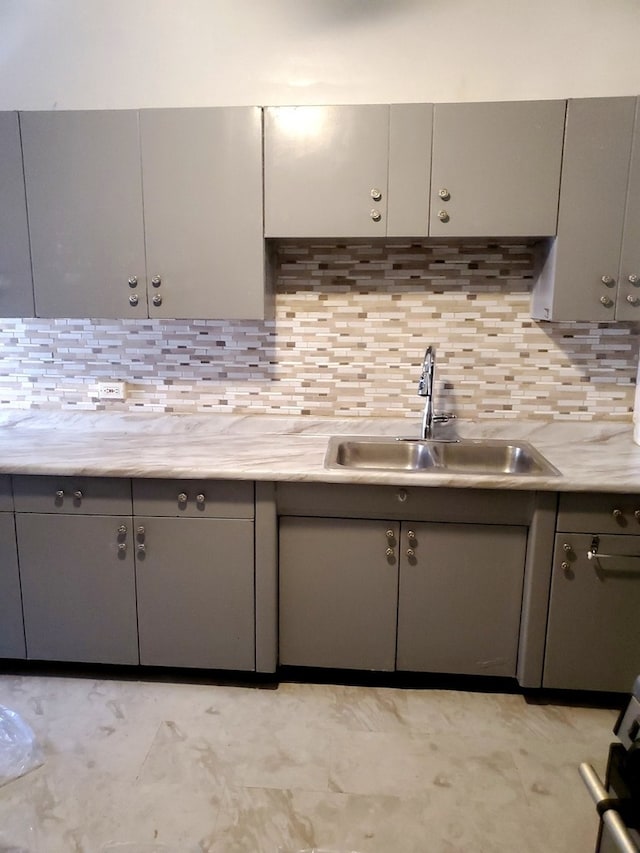 kitchen featuring gray cabinetry, tasteful backsplash, and sink