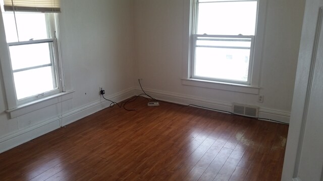 unfurnished room with a wealth of natural light and dark hardwood / wood-style flooring