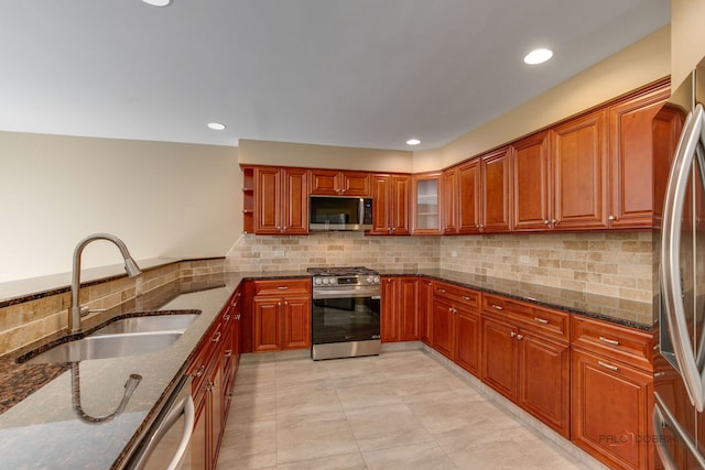 kitchen with decorative backsplash, dark stone countertops, appliances with stainless steel finishes, and sink