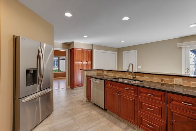 kitchen with light tile patterned floors, appliances with stainless steel finishes, sink, and dark stone counters