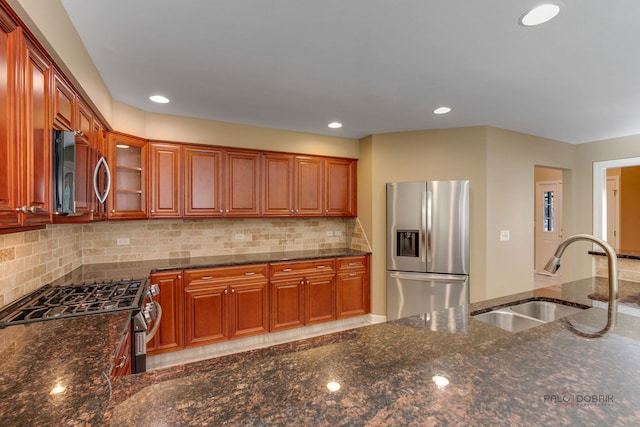 kitchen with dark stone countertops, appliances with stainless steel finishes, sink, and decorative backsplash