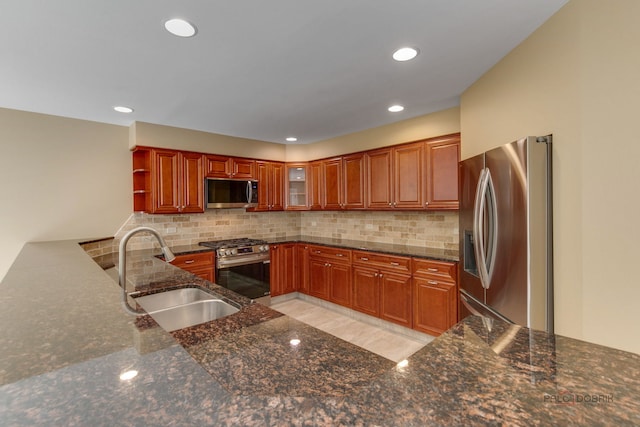 kitchen featuring appliances with stainless steel finishes, decorative backsplash, dark stone counters, and sink