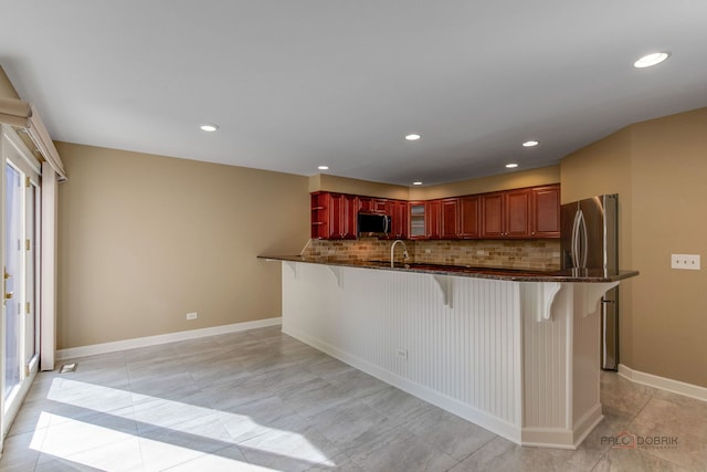 kitchen featuring appliances with stainless steel finishes, a kitchen breakfast bar, backsplash, and kitchen peninsula