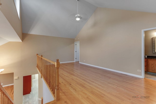 stairway with high vaulted ceiling, ceiling fan, and hardwood / wood-style floors