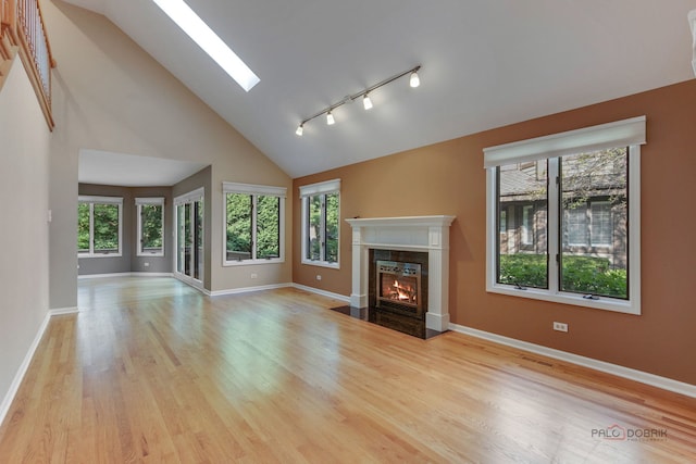 unfurnished living room featuring light hardwood / wood-style flooring, a premium fireplace, high vaulted ceiling, and rail lighting