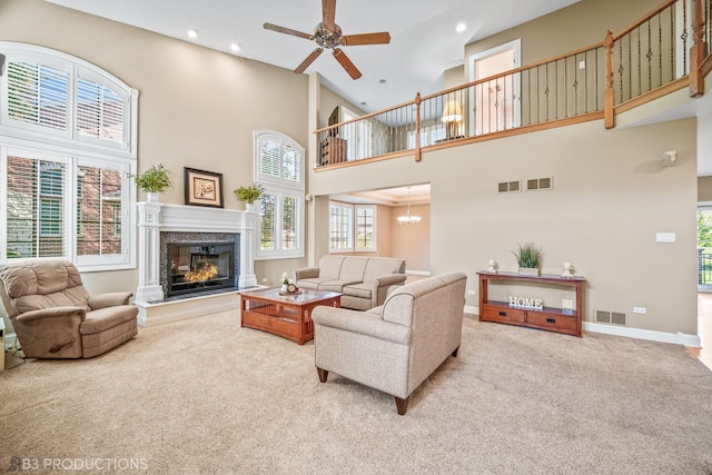 carpeted living room featuring a high ceiling, ceiling fan, and a high end fireplace