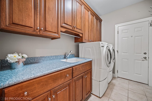 clothes washing area featuring cabinets, light tile patterned flooring, sink, and washer and dryer