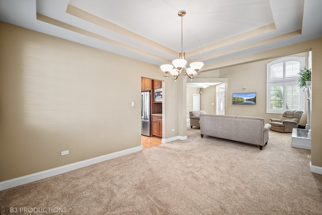 carpeted living room with a tray ceiling and an inviting chandelier