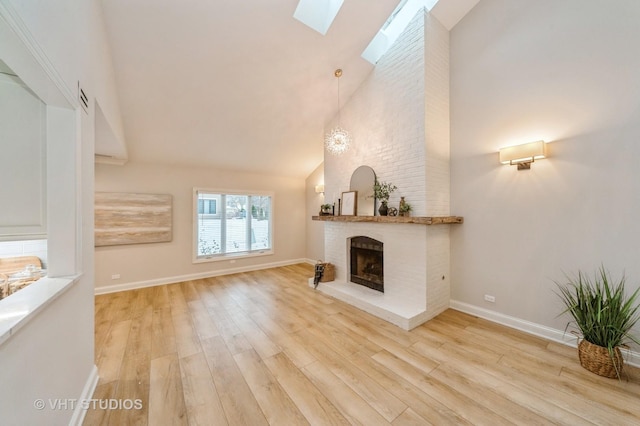 unfurnished living room featuring light hardwood / wood-style flooring, a fireplace, high vaulted ceiling, and a skylight