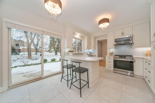 kitchen featuring white cabinets, a kitchen island, stainless steel appliances, and a chandelier