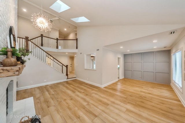 unfurnished living room with a chandelier, light wood-type flooring, and high vaulted ceiling