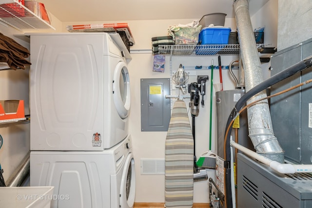 laundry area with water heater, stacked washing maching and dryer, and electric panel