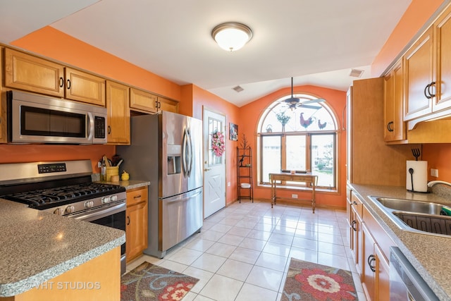 kitchen featuring appliances with stainless steel finishes, lofted ceiling, sink, and light tile patterned floors