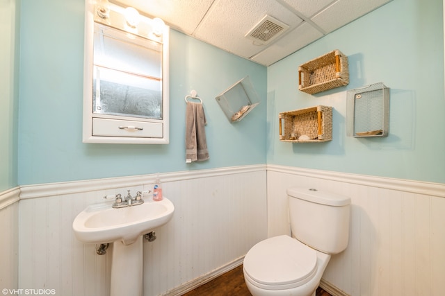 bathroom with a paneled ceiling and toilet