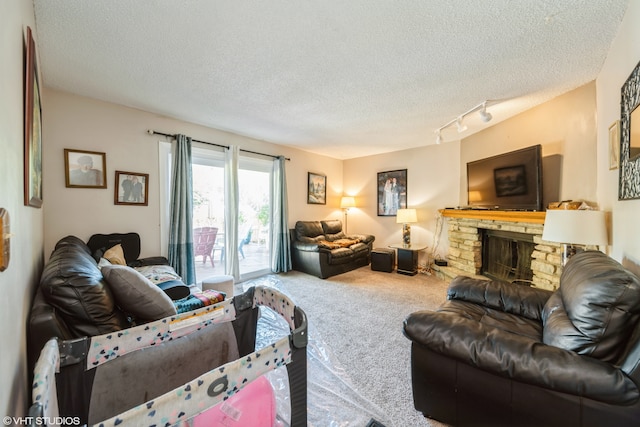 living room featuring a textured ceiling, track lighting, carpet floors, and a fireplace