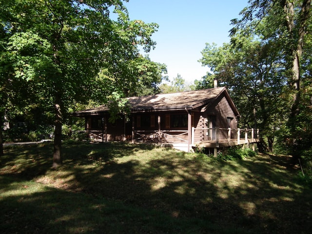 back of property featuring a deck and a lawn