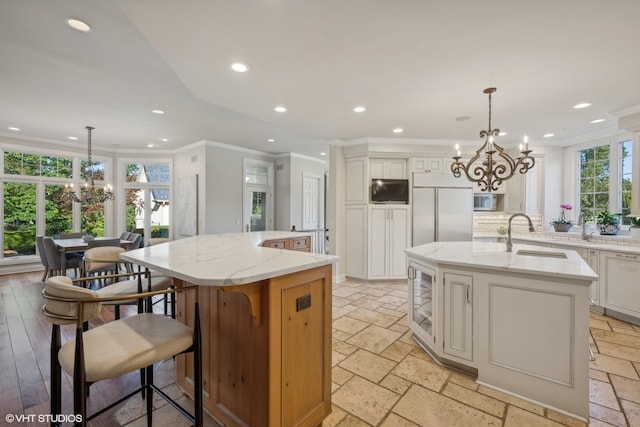 kitchen with a large island, sink, decorative light fixtures, and stainless steel built in refrigerator