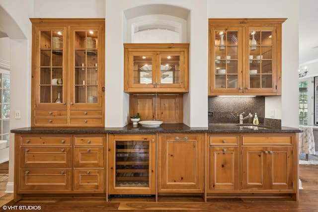 bar with wine cooler, dark stone countertops, dark wood-type flooring, and plenty of natural light