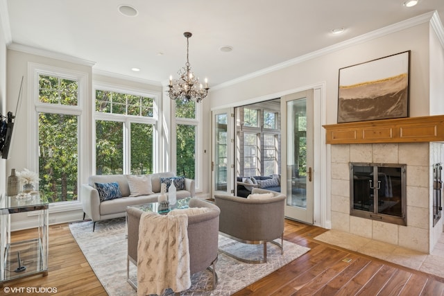 living room with hardwood / wood-style floors, crown molding, a notable chandelier, and a fireplace