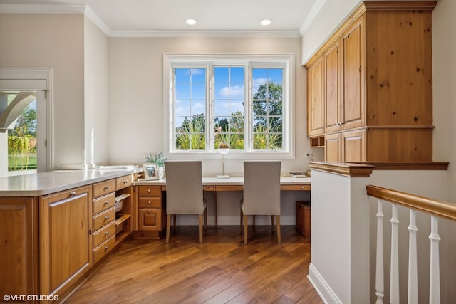 office space featuring built in desk, ornamental molding, wood-type flooring, and plenty of natural light