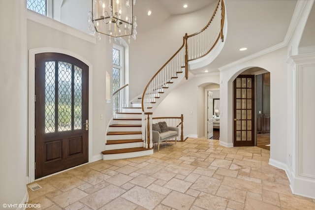 entryway featuring french doors, ornamental molding, and a high ceiling