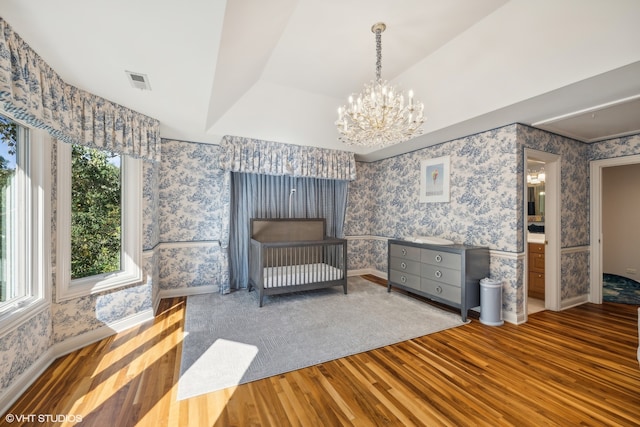 bedroom featuring hardwood / wood-style flooring, lofted ceiling, an inviting chandelier, and a raised ceiling