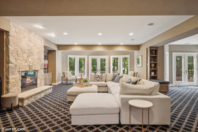 living room with a stone fireplace, french doors, carpet, and a wealth of natural light