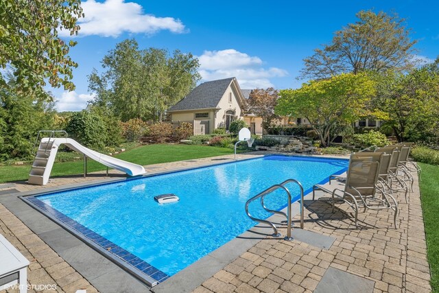 view of swimming pool with a water slide and a patio area