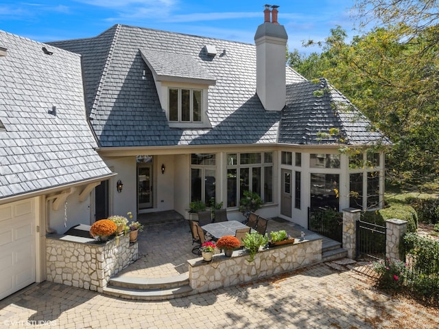 rear view of property with a patio and a garage