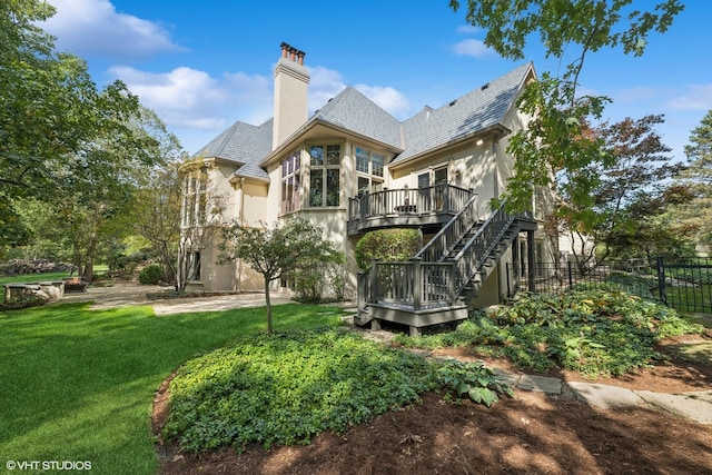 rear view of property with a wooden deck and a lawn