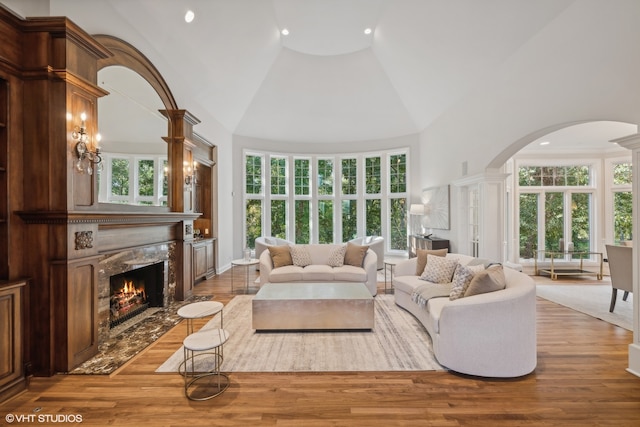 living room featuring high vaulted ceiling, a healthy amount of sunlight, and a premium fireplace