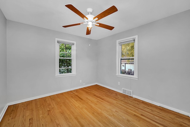 empty room featuring wood-type flooring, ceiling fan, and a healthy amount of sunlight