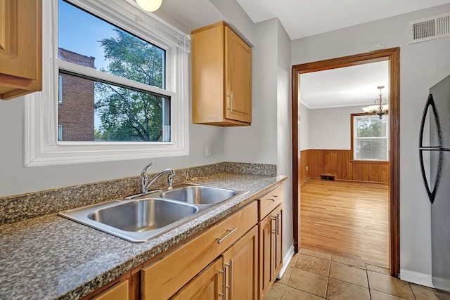 kitchen with sink, a notable chandelier, stainless steel refrigerator, light hardwood / wood-style flooring, and ornamental molding