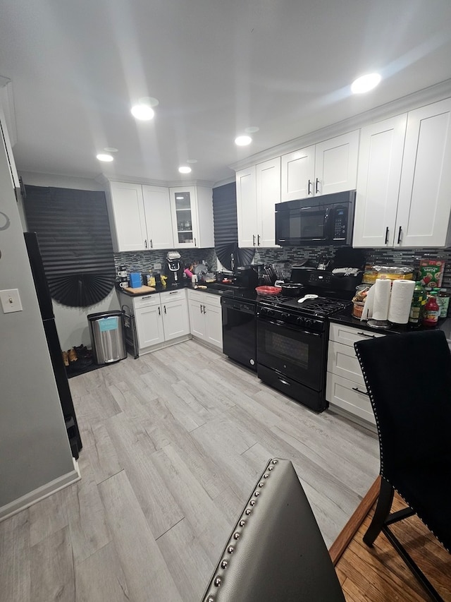 kitchen featuring white cabinets, light hardwood / wood-style flooring, backsplash, and black appliances