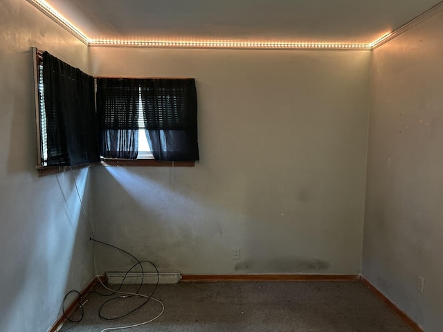 carpeted empty room featuring a baseboard heating unit