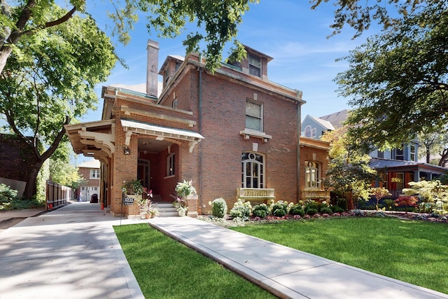 view of front of property featuring brick siding, a front lawn, and a chimney