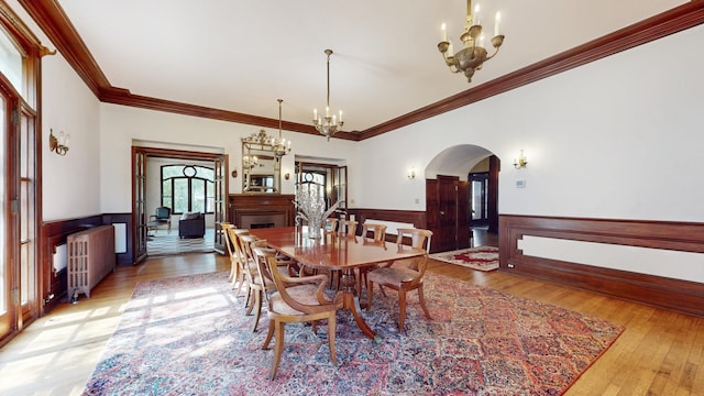 dining room featuring ornamental molding, radiator heating unit, and light wood-type flooring