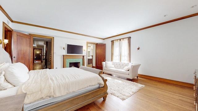 bedroom with a fireplace, crown molding, and light hardwood / wood-style flooring