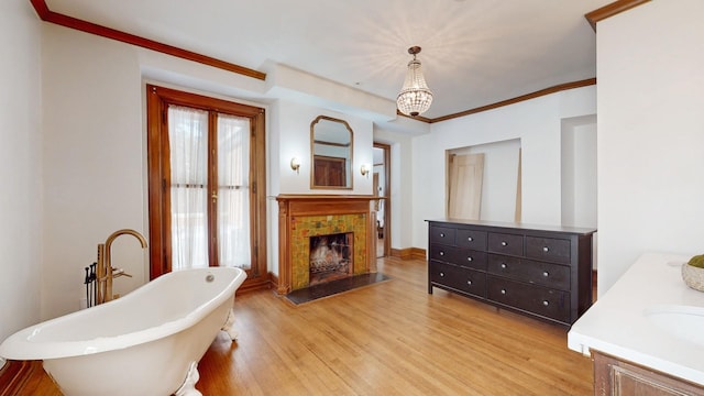 5235 S University Ave, Chicago, IL 60615 - bathroom featuring vanity, a soaking tub, wood finished floors, a fireplace, and a chandelier