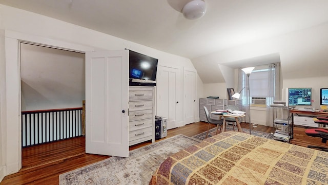 bedroom featuring dark wood-type flooring, lofted ceiling, and multiple closets