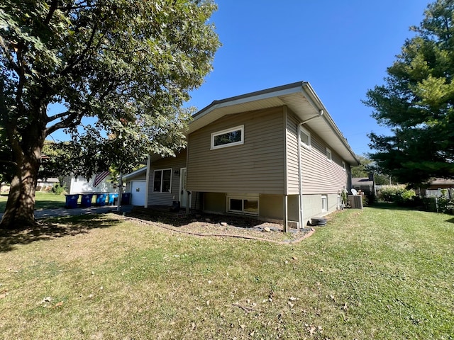 view of side of property with a yard, a garage, and central AC unit