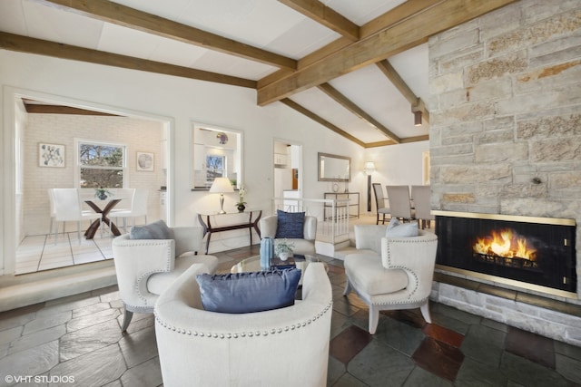 living room with vaulted ceiling with beams and a fireplace