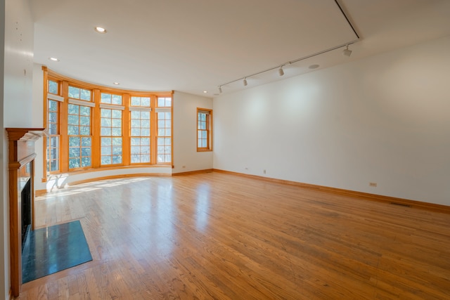 unfurnished living room with light hardwood / wood-style flooring and rail lighting