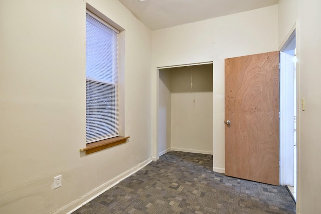 unfurnished bedroom with baseboards and dark colored carpet