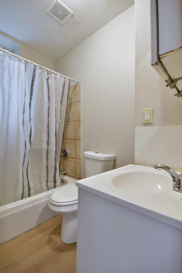 bathroom with shower / tub combo, visible vents, toilet, wood finished floors, and vanity